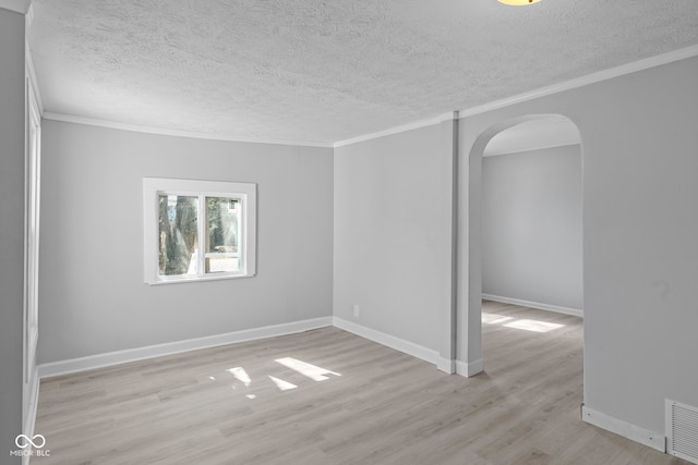 unfurnished room with arched walkways, light wood finished floors, a textured ceiling, and ornamental molding