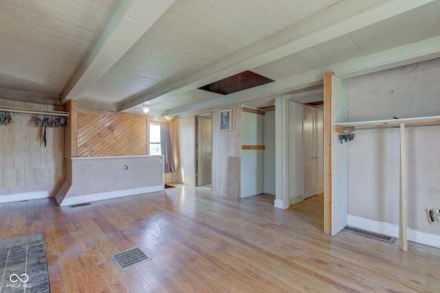 basement with visible vents, wood walls, and hardwood / wood-style floors