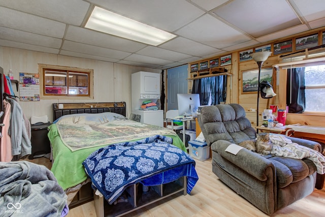 bedroom featuring wooden walls, wood finished floors, and a paneled ceiling