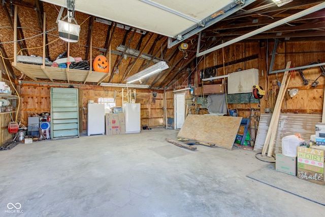 garage featuring wooden walls, a garage door opener, and freestanding refrigerator