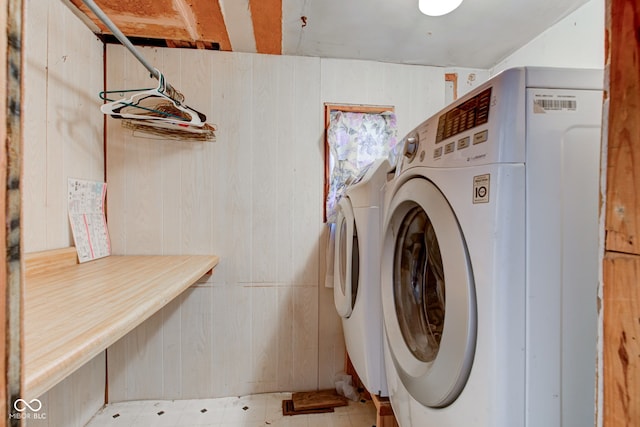 laundry area featuring washing machine and dryer, wood walls, and laundry area