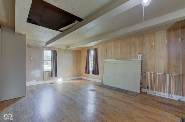 interior space featuring wood finished floors, baseboards, visible vents, beam ceiling, and wood walls