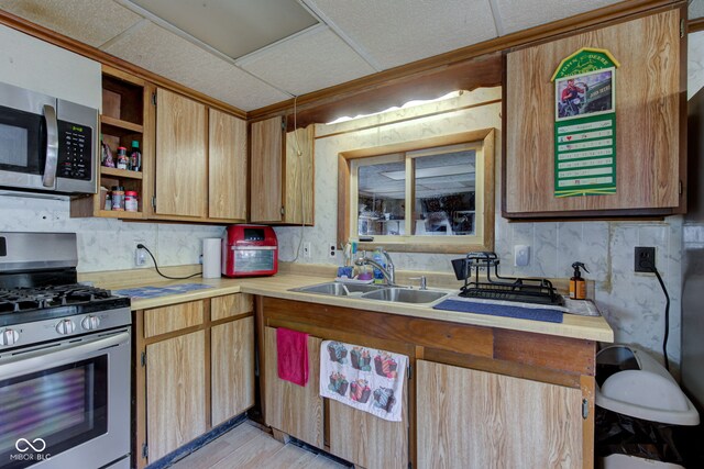 kitchen featuring a sink, stainless steel appliances, a drop ceiling, and light countertops