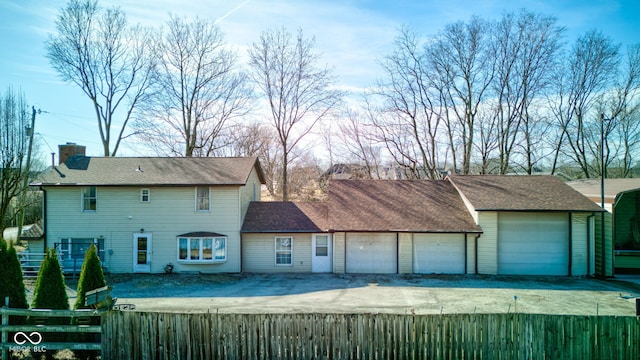 view of front of house featuring fence private yard, a garage, driveway, and a chimney