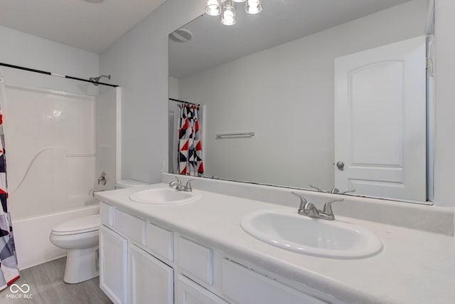 full bathroom featuring double vanity, toilet, wood finished floors, and a sink