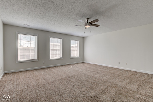 carpeted spare room with visible vents, baseboards, a textured ceiling, and ceiling fan