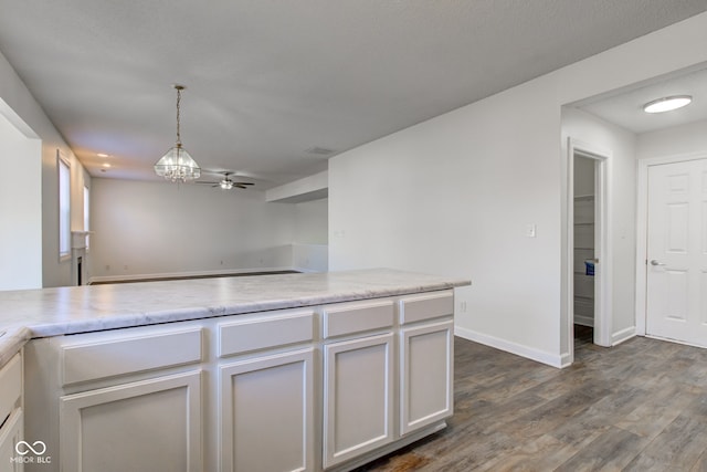 kitchen featuring dark wood-type flooring, ceiling fan, baseboards, light countertops, and hanging light fixtures