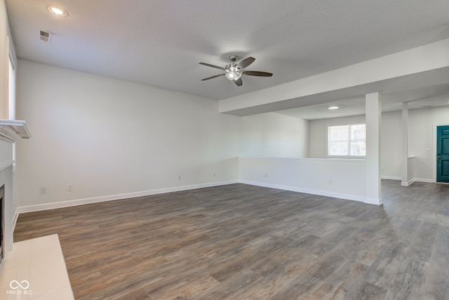 unfurnished living room featuring dark wood finished floors, a fireplace with flush hearth, baseboards, and visible vents