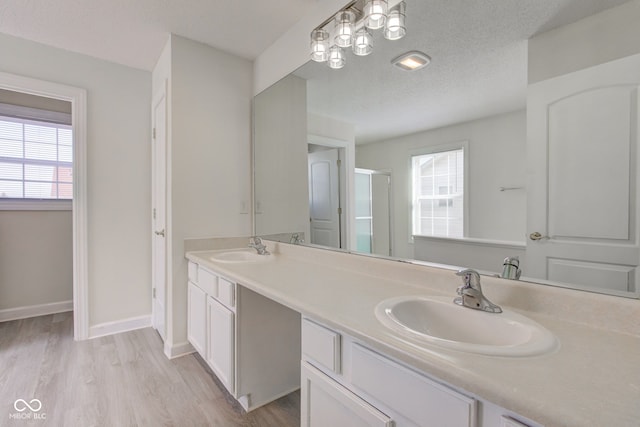 full bath with a sink, a textured ceiling, and a healthy amount of sunlight