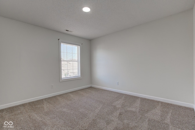 spare room featuring carpet flooring, visible vents, baseboards, and a textured ceiling