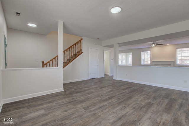 unfurnished living room with stairway, visible vents, dark wood-type flooring, and baseboards