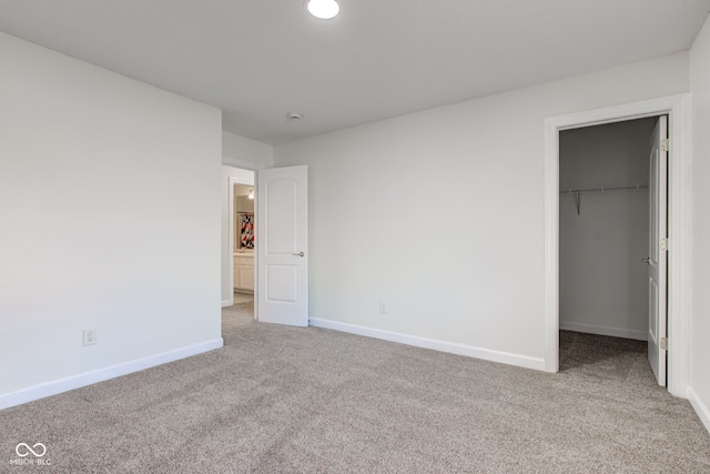 unfurnished bedroom featuring a spacious closet, carpet, baseboards, and a closet