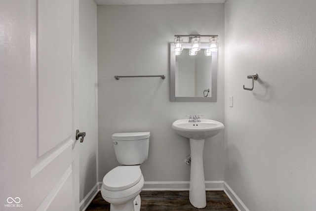 bathroom with a sink, baseboards, toilet, and wood finished floors