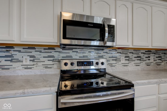 kitchen with light stone counters, decorative backsplash, appliances with stainless steel finishes, and white cabinets