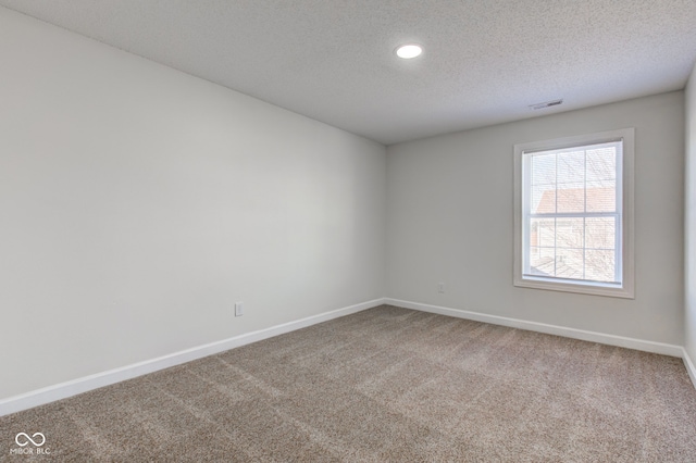 carpeted spare room featuring visible vents, a textured ceiling, and baseboards