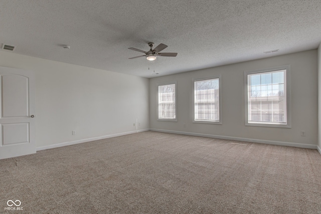 spare room with visible vents, baseboards, ceiling fan, a textured ceiling, and light colored carpet