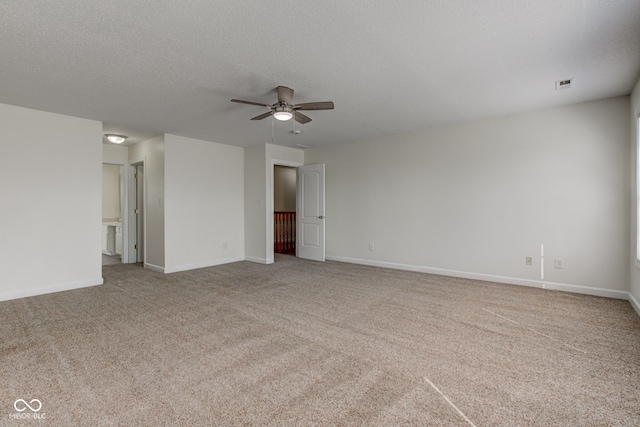 carpeted spare room with visible vents, baseboards, and a textured ceiling