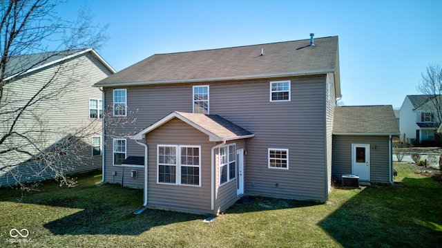 rear view of property with a yard, central AC unit, and a shingled roof