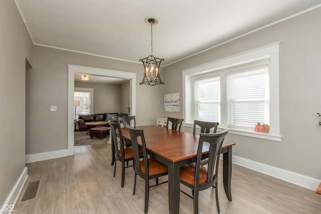 dining room featuring light wood-type flooring, visible vents, crown molding, baseboards, and a chandelier