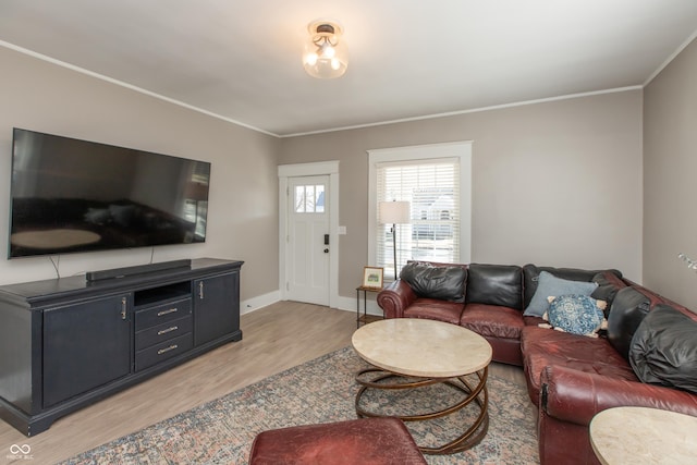 living area featuring light wood finished floors, crown molding, and baseboards