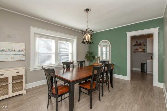 dining area featuring an inviting chandelier, baseboards, crown molding, and light wood-style floors