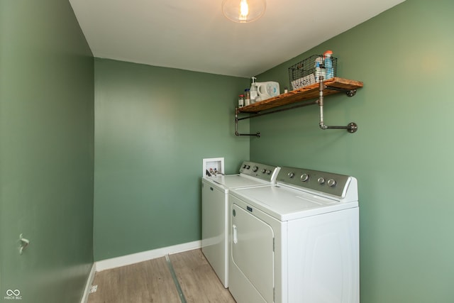 clothes washing area with laundry area, separate washer and dryer, light wood-type flooring, and baseboards