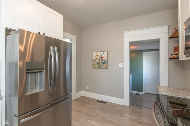 kitchen featuring visible vents, stainless steel refrigerator with ice dispenser, white cabinetry, light wood finished floors, and baseboards