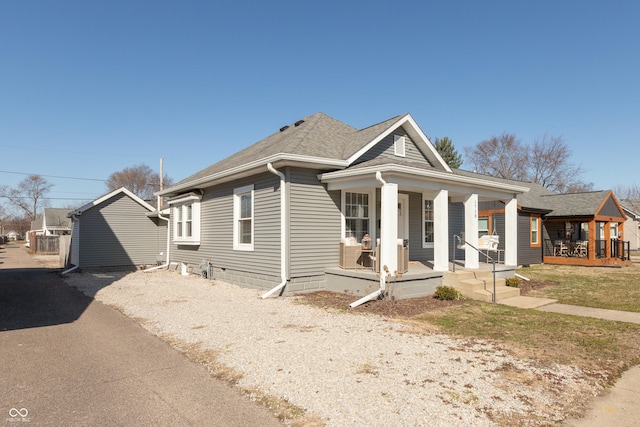 view of front of property with a porch, driveway, and roof with shingles