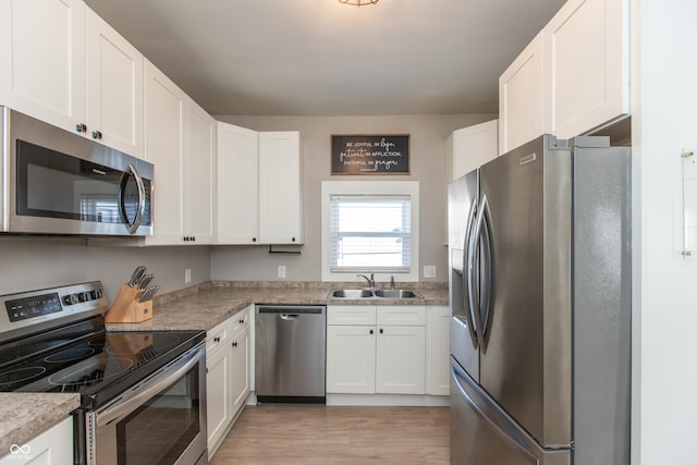 kitchen with light wood-style flooring, a sink, white cabinetry, stainless steel appliances, and light countertops