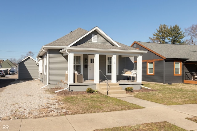 bungalow with a porch, a front yard, and a shingled roof