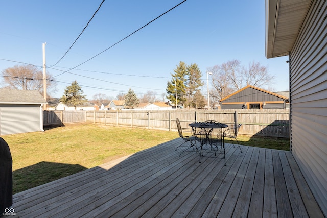 wooden terrace with outdoor dining area, a lawn, and a fenced backyard