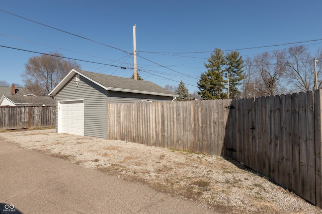 detached garage featuring driveway and fence