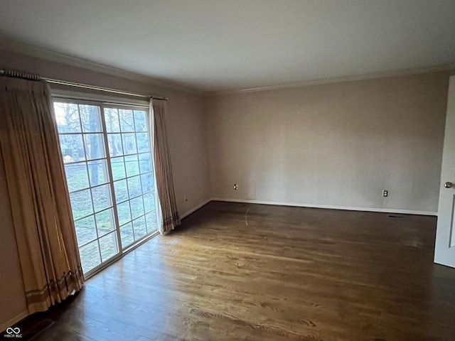 empty room featuring wood finished floors, baseboards, and ornamental molding