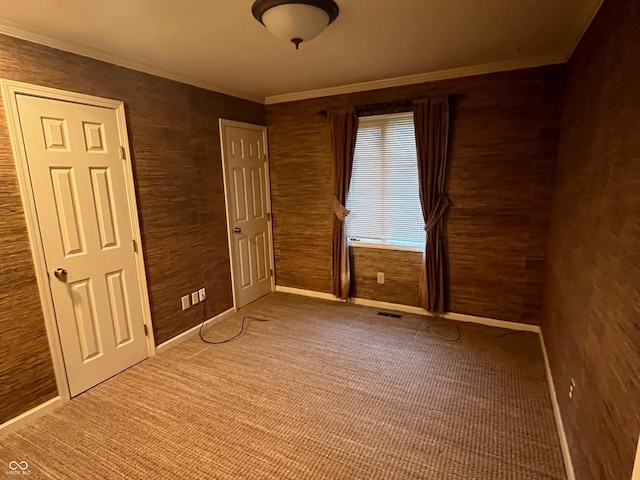 unfurnished bedroom with crown molding, baseboards, visible vents, and carpet floors