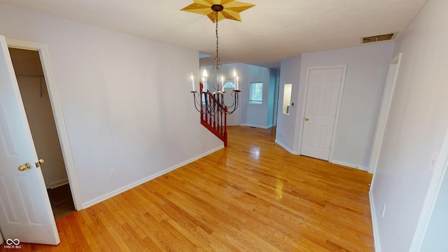 unfurnished dining area with an inviting chandelier, light wood-style flooring, baseboards, and visible vents