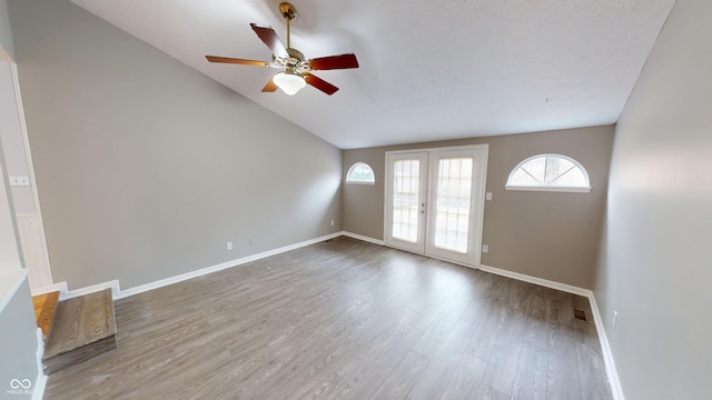 unfurnished living room featuring wood finished floors, baseboards, ceiling fan, vaulted ceiling, and french doors