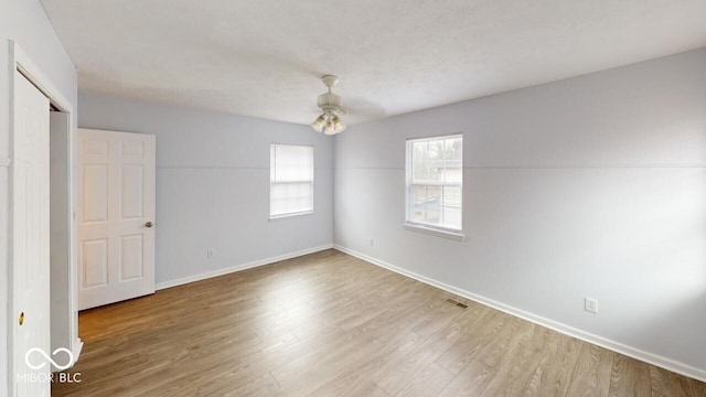 interior space featuring ceiling fan, visible vents, baseboards, and wood finished floors