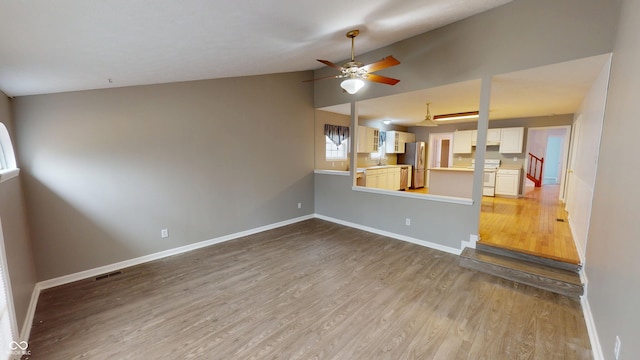 unfurnished living room featuring lofted ceiling, baseboards, and ceiling fan