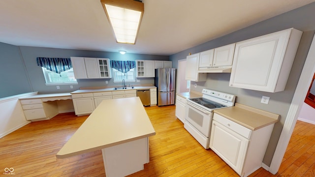 kitchen featuring light wood-style flooring, white cabinets, under cabinet range hood, appliances with stainless steel finishes, and a center island