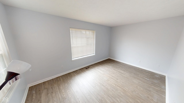 spare room with baseboards and wood finished floors