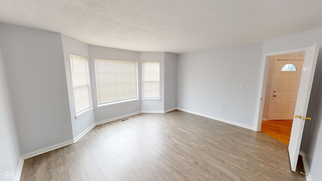 empty room featuring wood finished floors, baseboards, and a textured ceiling