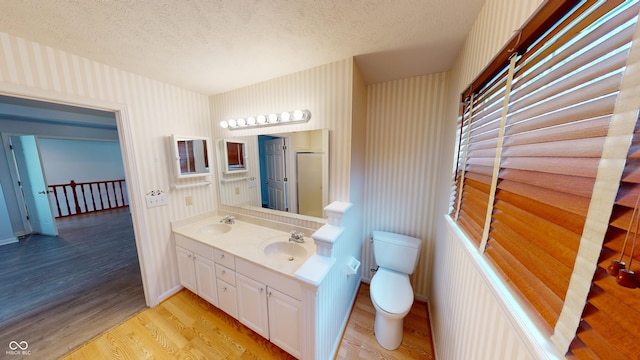 full bath featuring a sink, a textured ceiling, toilet, and wood finished floors