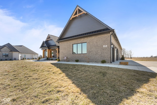 view of front of house with driveway, a standing seam roof, a front yard, a garage, and brick siding