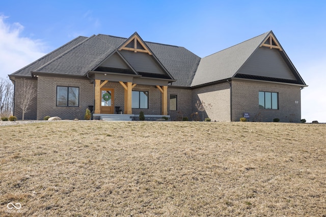 view of front facade with brick siding, a front lawn, and a shingled roof