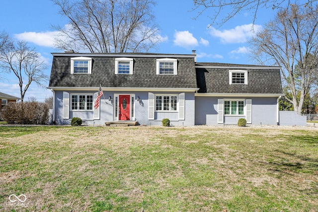 view of front of home with mansard roof, brick siding, roof with shingles, and a front yard