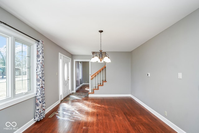 1310 Bowman Dr, Greenfield, IN 46140 - empty room with a chandelier, stairs, dark wood-type flooring, and baseboards