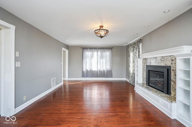 1310 Bowman Dr, Greenfield, IN 46140 - unfurnished living room featuring a premium fireplace, wood finished floors, visible vents, and baseboards