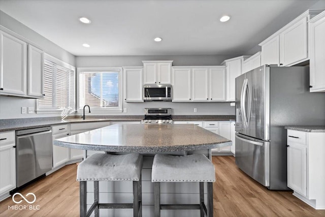 kitchen featuring light wood-style flooring, appliances with stainless steel finishes, a breakfast bar, and white cabinetry