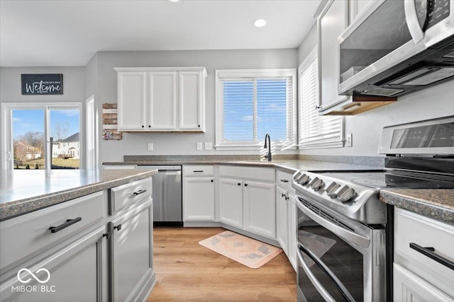 kitchen with light wood-style flooring, recessed lighting, a sink, stainless steel appliances, and white cabinets