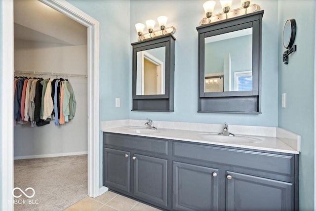 full bath with double vanity, a walk in closet, baseboards, and a sink